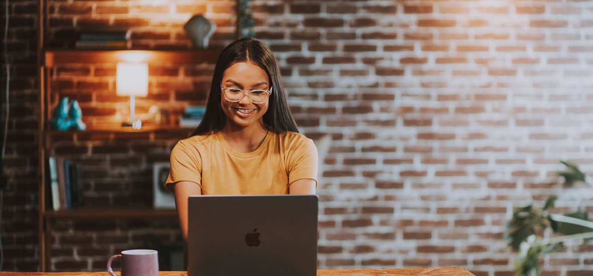 Happy young woman confidently using her Apple Macbook Pro with BCare Extended Warranty